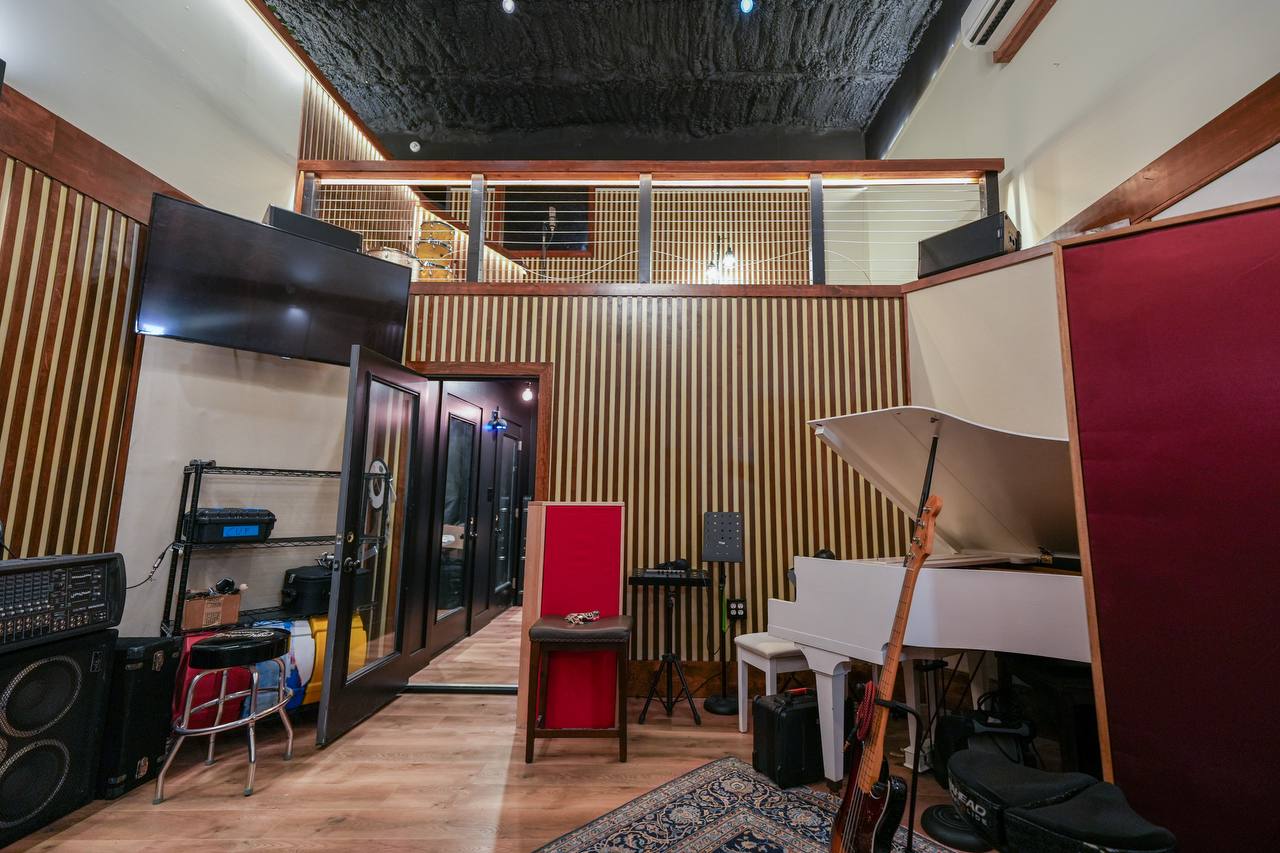 Live room — loft level, white baby grand, acoustic panels